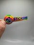 A hand holding a holographic sticker with the text “24 HR STICKERS” in bold letters, reflecting rainbow colors.